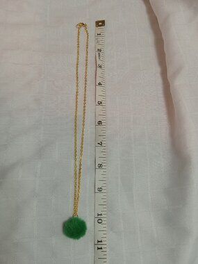 Handmade necklace with a small pom-pom and gold-colored accent hooks and chains